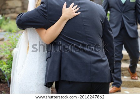 View of a father congratulating her newly wed daughter with a hug. 
