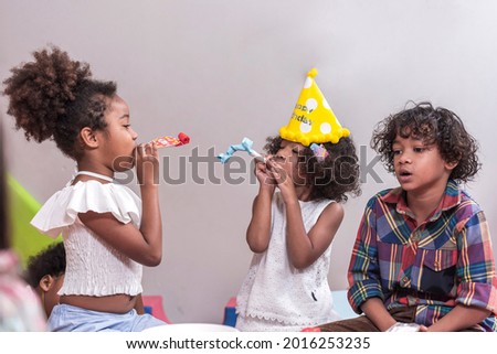 Group of happy enjoy kids blow in multicolor party blowers with friend kids birthday celebratiion party.
