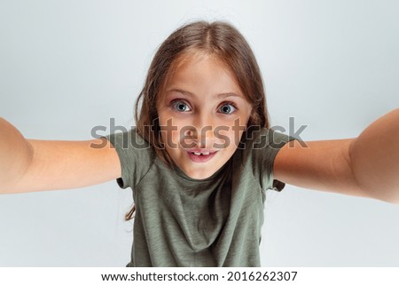 Close-up portrait of beautiful preschool smiling girl looking at camera isolated on white studio background. Copyspace for ad. Happy childhood, education, emotions, facial expression concept.