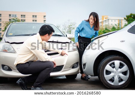 Two drivers check for damage after a car accident before taking pictures and sending insurance. Online car accident insurance claim idea after submitting photos and evidence to an insurance company.