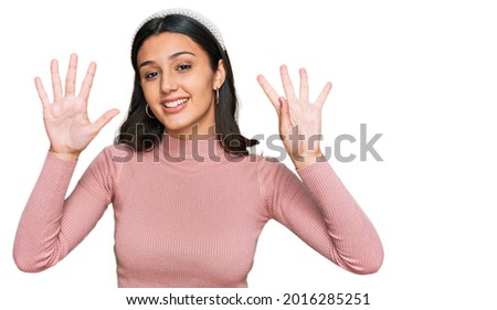 Young hispanic girl wearing casual clothes showing and pointing up with fingers number nine while smiling confident and happy. 
