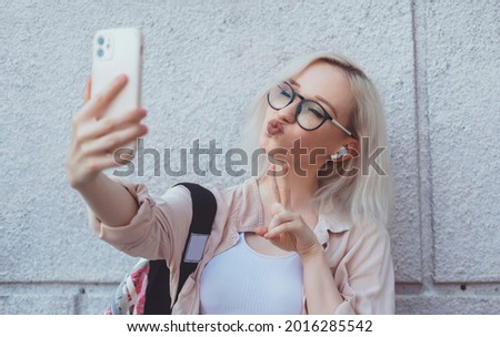 Young beauty girl purple hair make selfie on smartphone, happy face, outdoor hipster portrait on the street, smile happy face, listen music on headphones, Amsterdam street, dance, player,photo concept Royalty-Free Stock Photo #2016285542