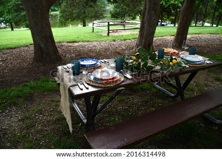 A picnic table with plates and other dishes on it. There are candles and a lemon garland on the table. Picture taken in O’Fallon, Missouri.