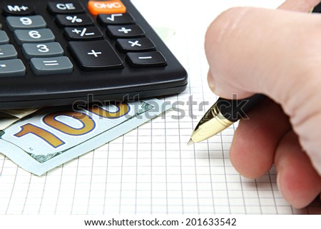 Hand with pen and money, calculator, notepad.