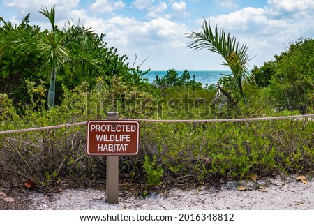 Sign and barrier rope at edge of protected wildlife habitat by trail on Sanibel Island along the Gulf Coast of Florida. Foreground focus.