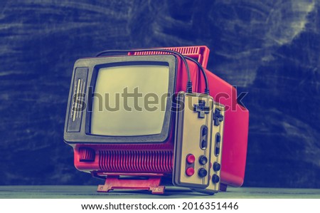 Retrogaming. Video game competition. Old TV with gamepads on blackboard background