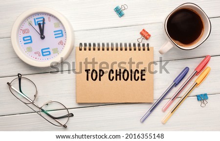 TOP CHOICE - an inscription on a notebook on the table with a clock, coffee and glasses