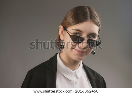girl in white blouse, black jacket and sunglasses posing
