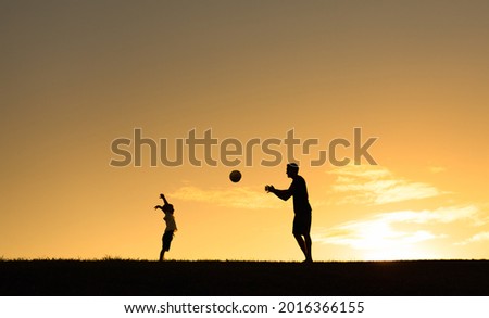 Father son silhouette having fun playing together throwing ball in the park. Parenting, family lifestyle. 