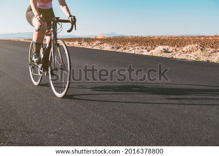 Close-up of the legs of a female cyclist while riding on a road during sunset. Cycling concept. Sport concept.