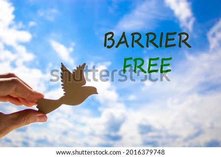 Barrier free symbol. Businessman hand holding wooden bird on cloud blue sky background. Words 'Barrier free'. Business, diversity, inclusion, belonging and barrier free concept. Copy space.