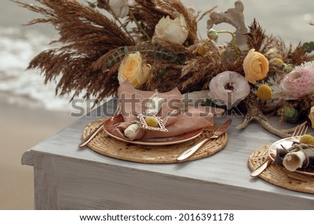 A table  designed for a boho style event with an eucalyptus, vintage plates and other rustic touches. On seaside in the sand dunes