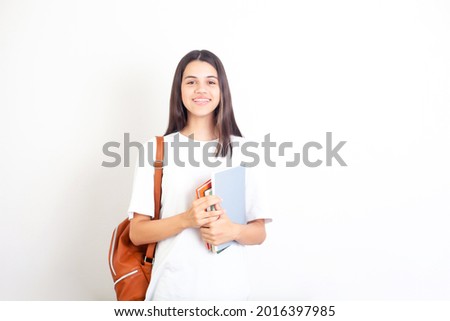 Portrait of a schoolgirl with a backpack and books. The student girl looks into the camera and smiles. White background. A place for text. Academic year. semester. exam. Science. High quality photo