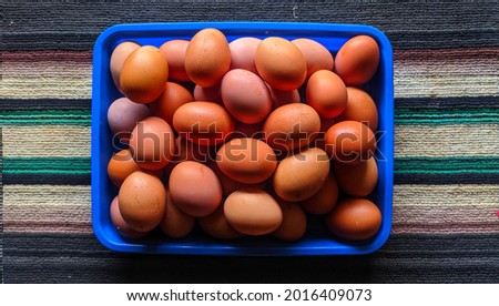 stock raw chicken eggs in a blue container