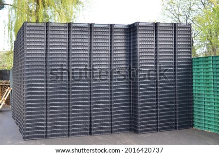Many black plastic storage boxes piled in stock.