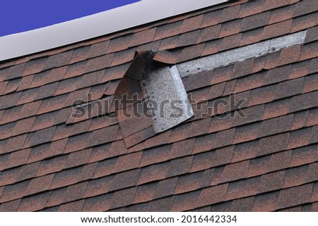 Damaged Brown Roof Shingle - Wind Damage Royalty-Free Stock Photo #2016442334
