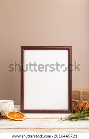 Brown wooden frame mockup with cup of coffee and cake on brown background. Blank, side view, still life.