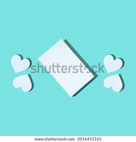 Creative Pattern from Cute paper heart and white cover book on turquoise-mint background. Modern photo. Concept National Book Lovers Day. happy holydays. Romantic, love storytelling.Copy space.Mock up