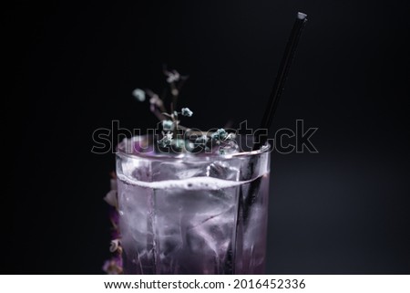 luxury violet fizz cocktail drink with flower decoration on black background