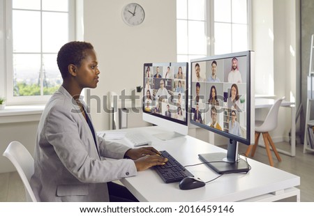 Business people working together in Covid lockdown quarantine, talking and discussing new projects. Team manager looking at two desktop computers during virtual staff training meeting with colleagues Royalty-Free Stock Photo #2016459146