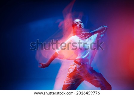 Dancing young mixed race girl enjoying moving in colorful neon studio light. Long exposure. Ethnic fiery dance