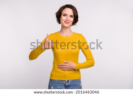 Photo of young girl happy positive smile hands on belly show thumb-up fine healthy isolated over grey color background Royalty-Free Stock Photo #2016463046