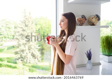 Profile side view portrait of attractive calm dreamy girl drinking cacao at home light white living room house indoors