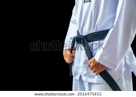 Taekwondo traditional master judo aikido man hand hold black-belt on black background for advertising. The karate man standing with black belt isolated on black with copy space. Royalty-Free Stock Photo #2016475652