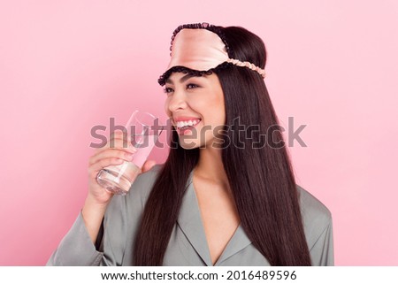 Photo of shiny cute lady sleepwear mask drinking water smiling isolated pink color background