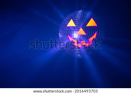 Halloween party pumpkin disco ball, jack o'lantern with shiny blue rays in smoke