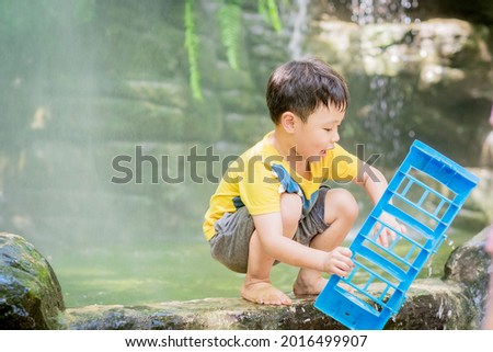 Cute little boy enjoy playing toys near waterfall. Kids studying and learning nature. Soft focus. Background.