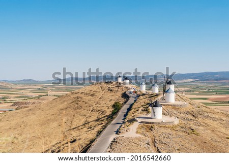 Road in the middle of windmills on the top of a hill