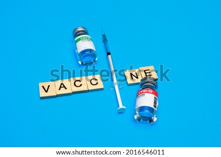Wooden English alphabet block and medical syringe arranged into word with sealed glass capsule of covid-19 vaccine expressing immunity dose of pharmacy to prevent disease outbreak