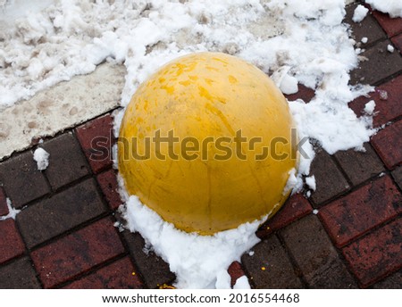 Concrete parking bollard (barrier, block) on the road in winter. 