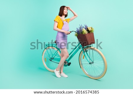 Full length photo of young happy woman look forward hand head biker free time isolated on teal color background