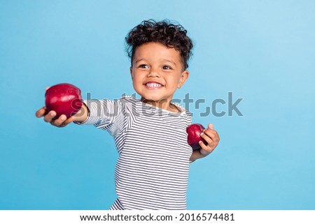 Portrait of attractive cheerful boy giving you fresh apple share isolated over vibrant blue color background Royalty-Free Stock Photo #2016574481