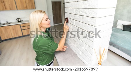 Woman at home using smart thermostat, automation domestic system