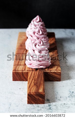 Homemade zefir (zephyr russian dessert with agar agar) pink round soft raspberry marshmallow meringue. Wooden board on a dark background. Vertical.