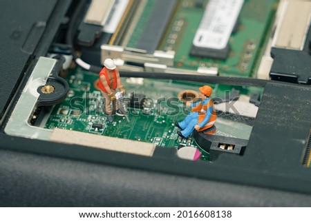Miniature people : worker and technician repairing electronic mainboard of computer. 