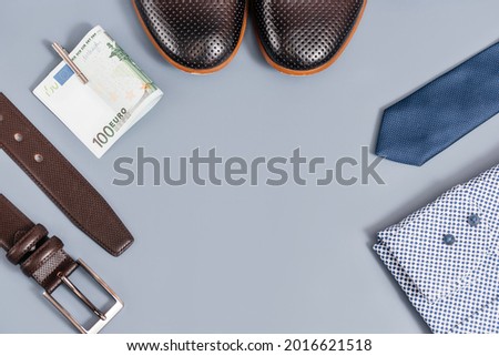 Men's clothes and accessories.tie and shoes shirt, belt money. on a blue background, copy space.Top view.