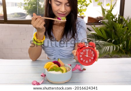  Fast Intermittent with Red clock  in lunch time and woman at the kitchen background-Heathy eating diet concept
