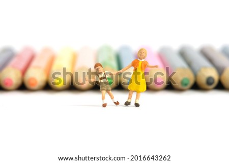 Miniature people toy figure photography. Drawing class concept. A group of kids playing on colorful pencil, isolated on white background. Image photo