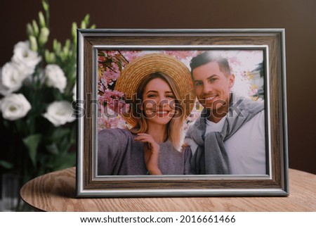 Framed photo of happy couple on wooden table indoors