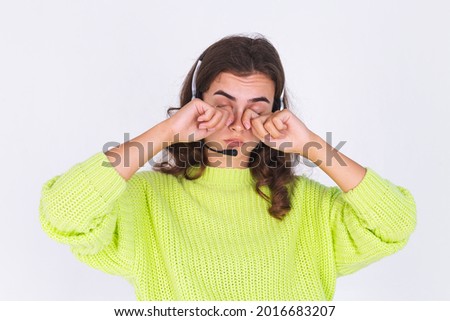 Young beautiful woman with freckles light makeup in sweater on white background with headphones helpline worker call centre manager sad tired bored
