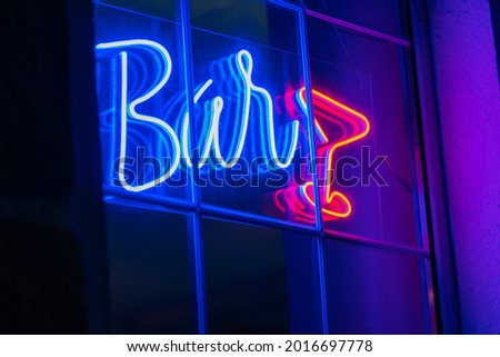 Beautiful blue neon bar sign with a red neon glass on the window. Advertising neon sign glows in the dark