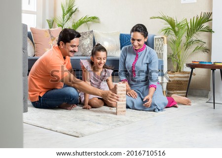 Happy Family sitting On floor Playing With The Wooden Blocks At Home