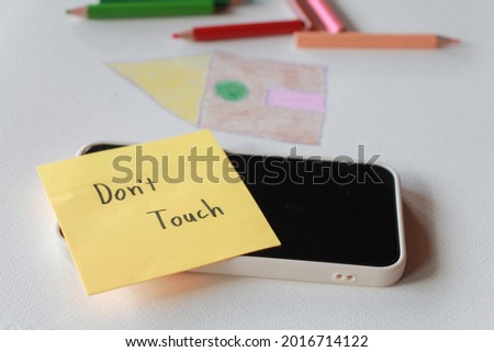 Text "don'touch" on paper note on smart phone. Digital detox, dependency on techno gadget and devices concept.