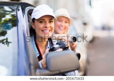 smiling female tourists on road trip looking out of window