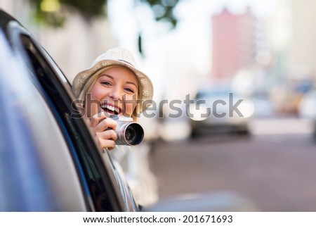 cheerful young woman traveling in a car and taking photos