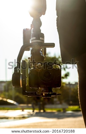 Gimbal being held by a videographer at sunset. Audiovisual concept